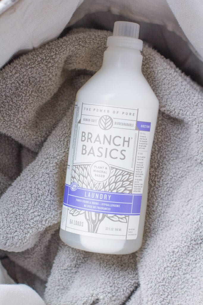 Branch Basics laundry detergent on top of grey towels in the laundry bin
