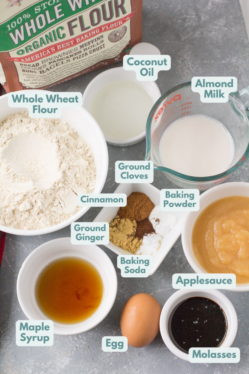 Ingredients for healthy gingerbread loaf laid out in small bowls on a grey background