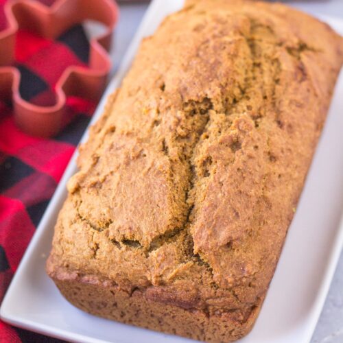 Healthy Gingerbread Loaf on a white rectangle dish with a red checked linen and a cookie cutter off to the side