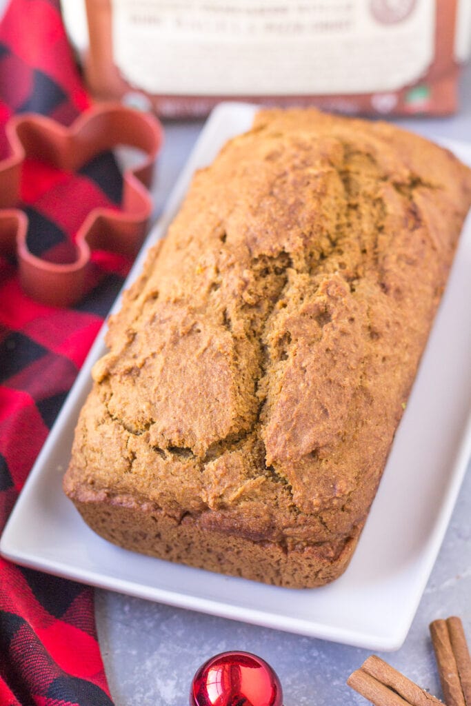 Healthy Gingerbread Loaf on a white rectangle dish with a red checked linen and a cookie cutter off to the side
