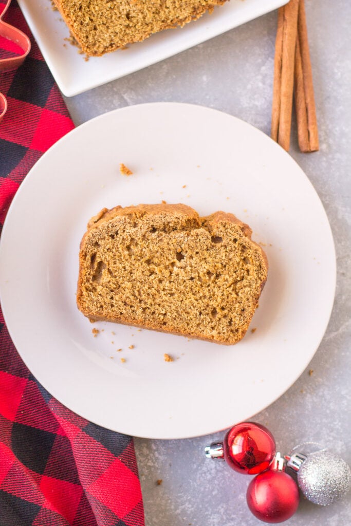 a slice of healthy gingerbread loaf on a white plate on a grey background in a christmas scene