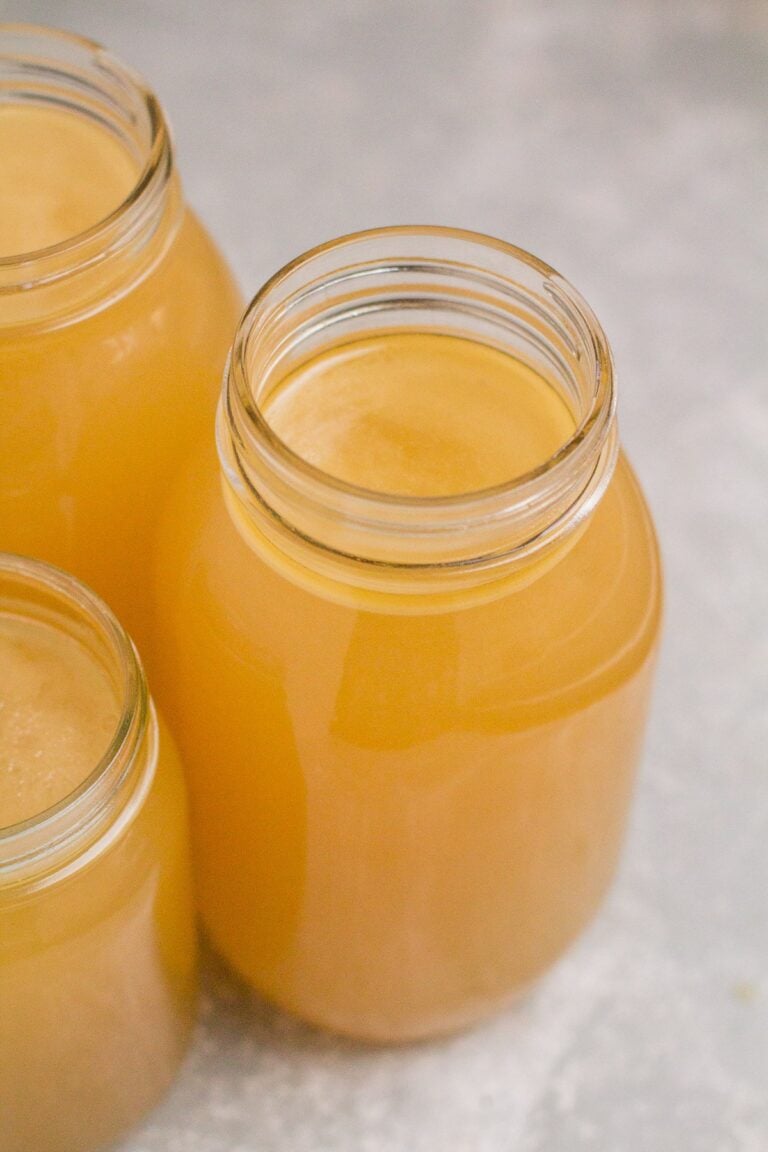 Instant Pot Bone Broth in glass jars on a grey background.
