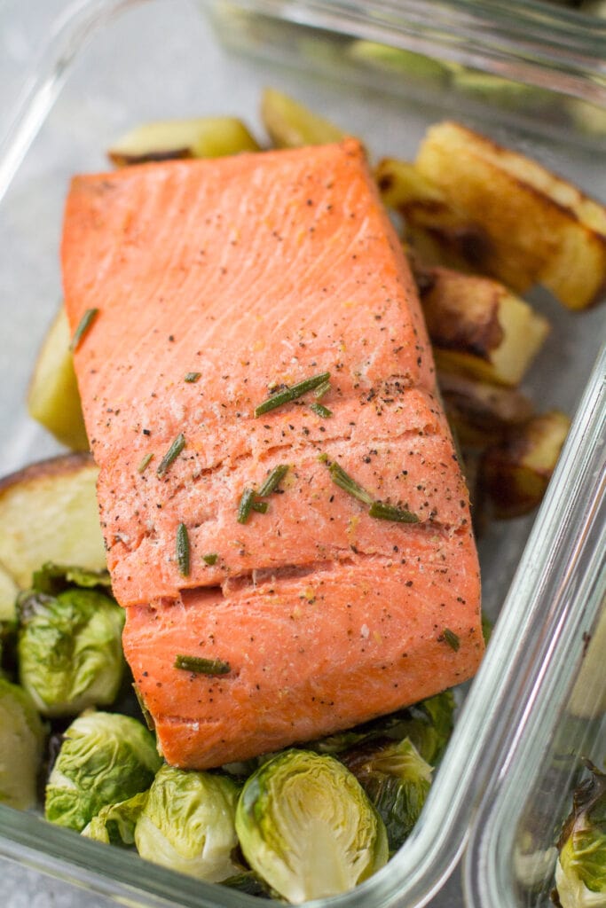 A an overhead shot of a paleo, whole30, healthy baked salmon piece on top of potatoes and brussels sprouts