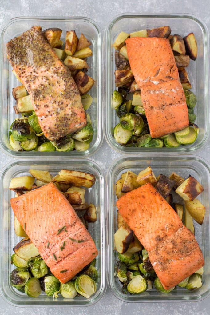 4 meal prep containers with salmon, brussels sprouts and potatoes in them.
