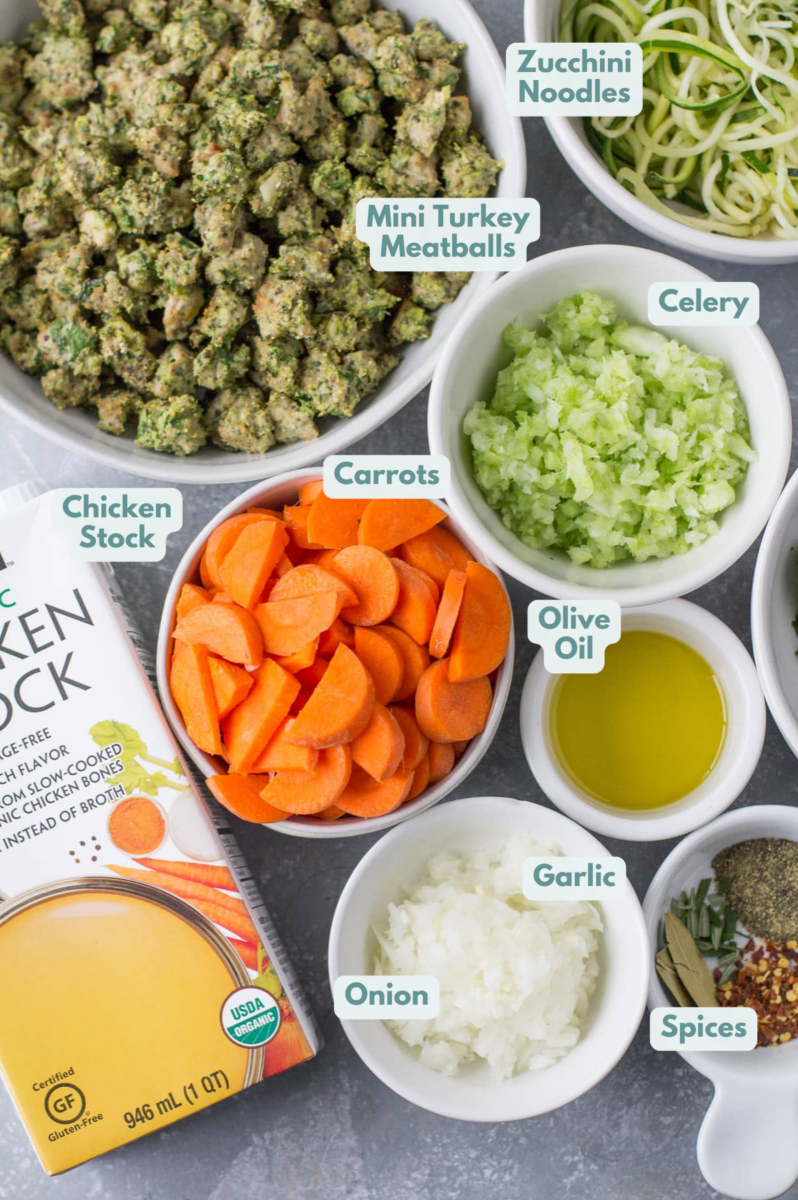 Ingredients for Healthy Italian Wedding Soup laid out on a grey background in small white bowls.