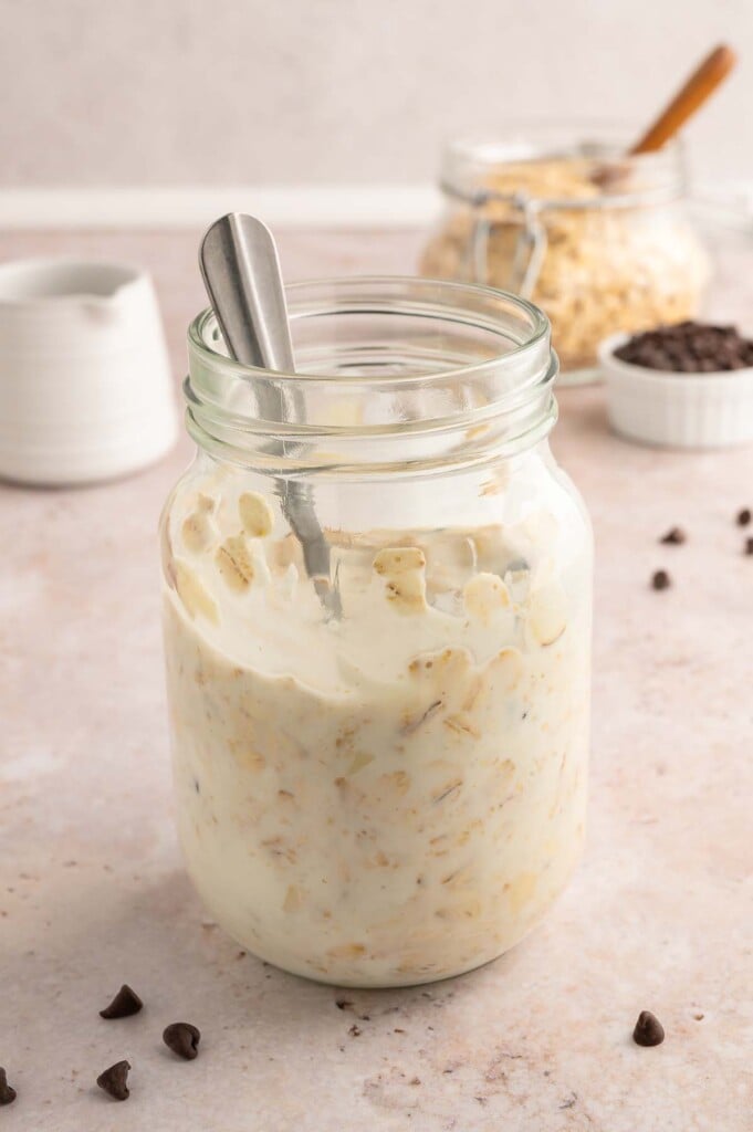Almond joy overnight oats in a clear jar being mixed together.