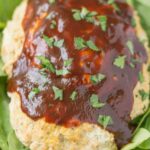 A close up of BBQ Chicken Meatloaf on a white plate with spinach