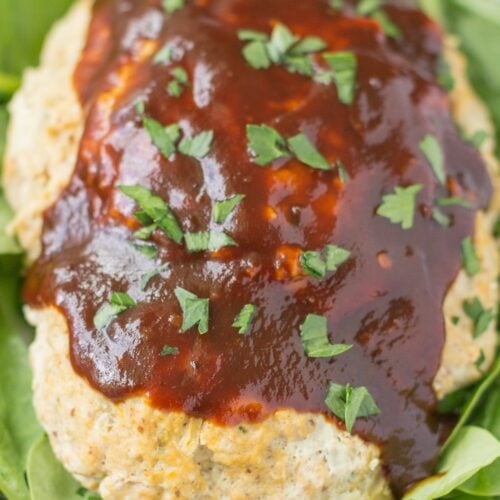 A close up of BBQ Chicken Meatloaf on a white plate with spinach