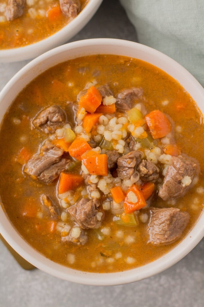 AA close up of healthy beef barley soup in a white bowl.