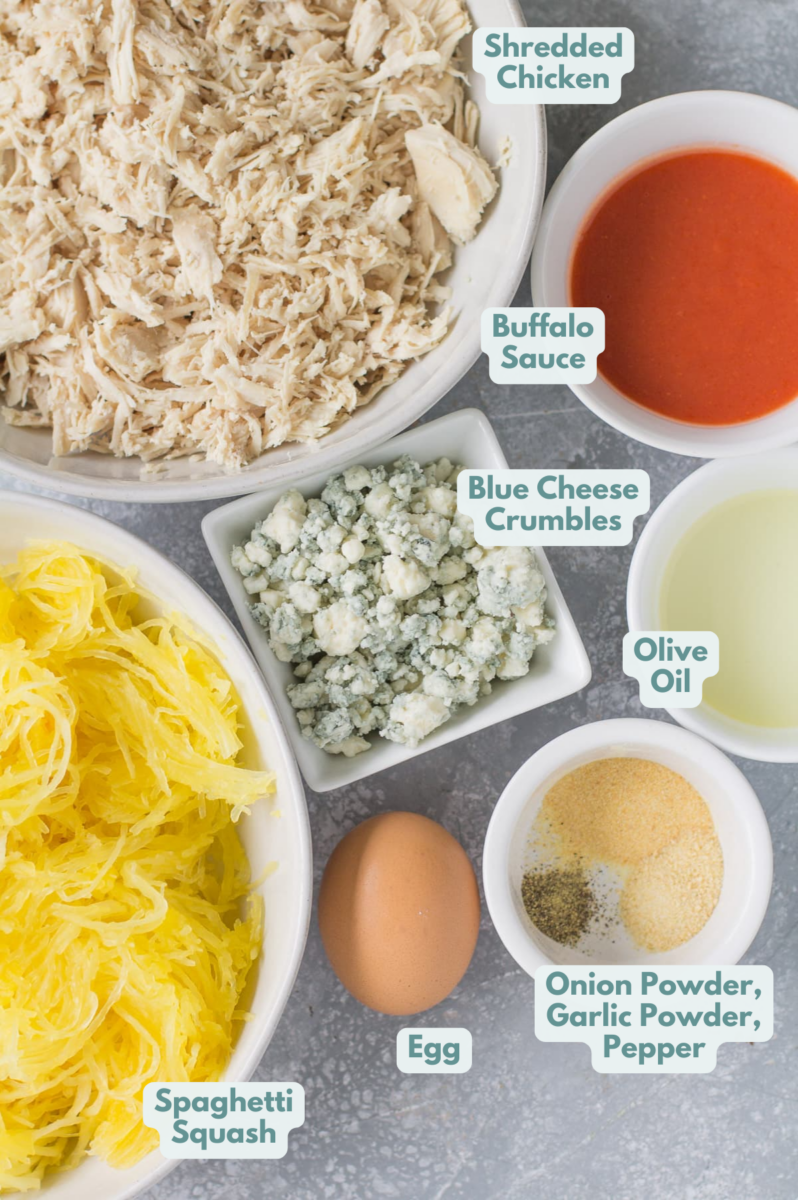 Ingredients for Buffalo Chicken Spaghetti Squash Casserole on a grey background all laid out in small white bowls.