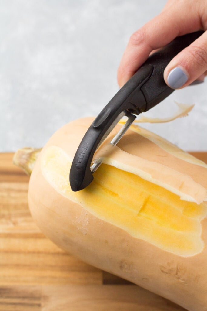 Butternut squash being peeled on a cutting board