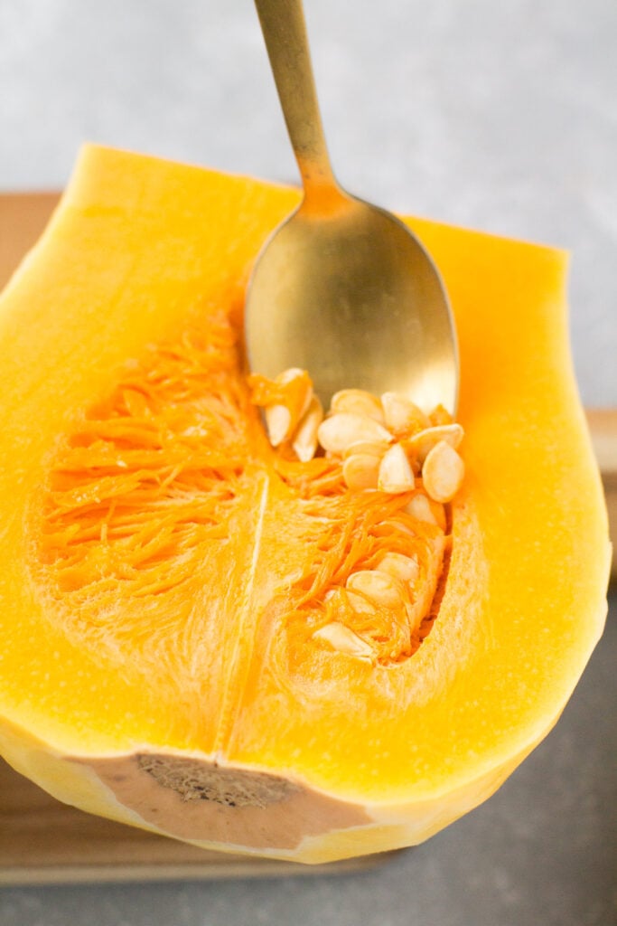 seeds being scooped out of butternut squash