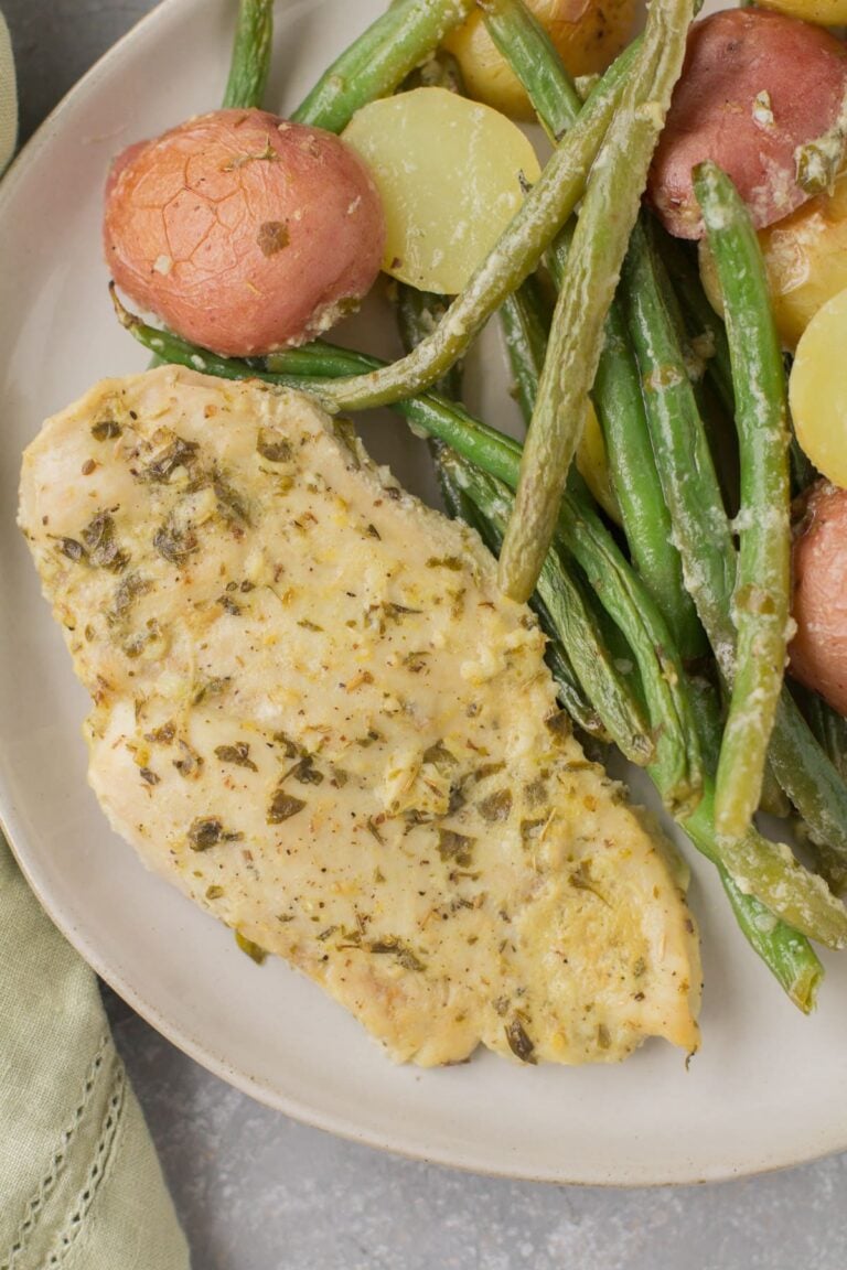 An overhead shot of Lemon Garlic Chicken Dinner on a white plate with a grey background