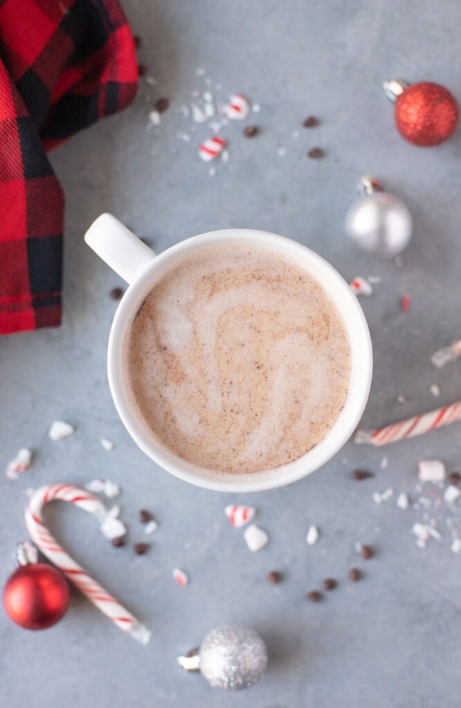 Close up of Healthy Peppermint Mocha Recipe with ornaments, candy canes and chocolate off to the side.
