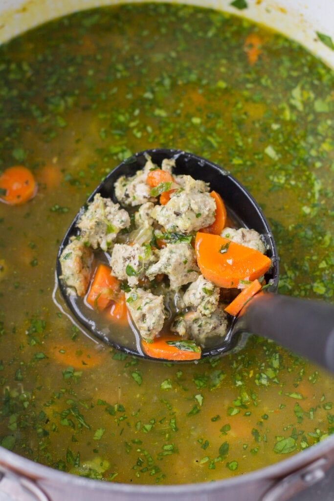 a close up of italian wedding soup being scooped out of a pot