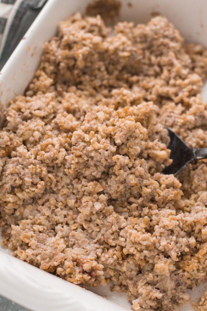 fluffy steel cut oats in a white baking dish with a serving spoon