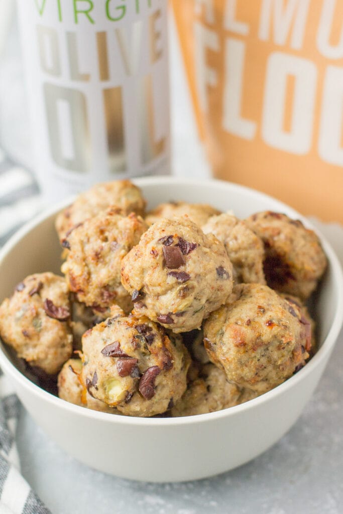 Greek Ground Turkey Meatballs in a white bowl with olive oil and almond flour in the background