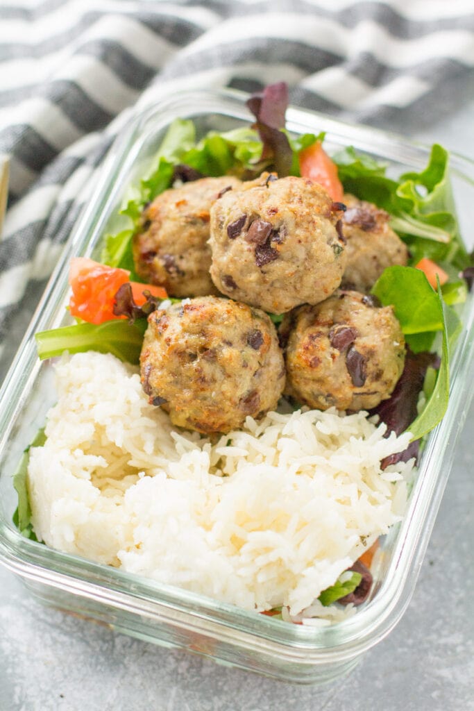 Juicy turkey meatballs in a meal prep container with rice off to the side.