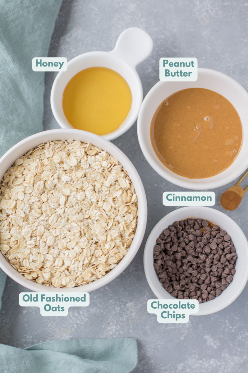 Ingredients for peanut butter chocolate in small white bowls granola on a grey background with a blue linen