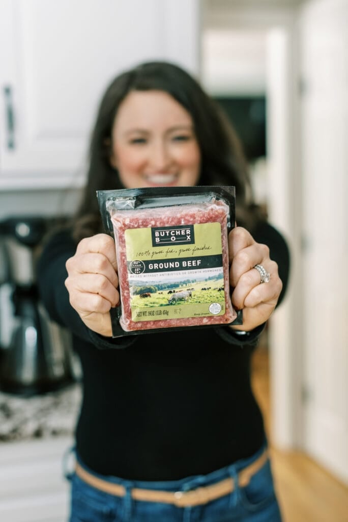 A girl holding up butcher box ground beef - giving an honest butcher box review