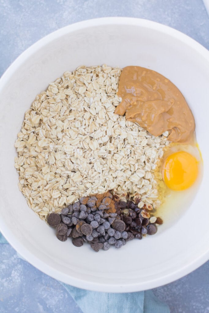 A close up of chocolate peanut butter oatmeal ingredients in a white b owl