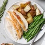 an overhead shot of Crockpot Whole Chicken sliced on a white plate with veggies and potatoes
