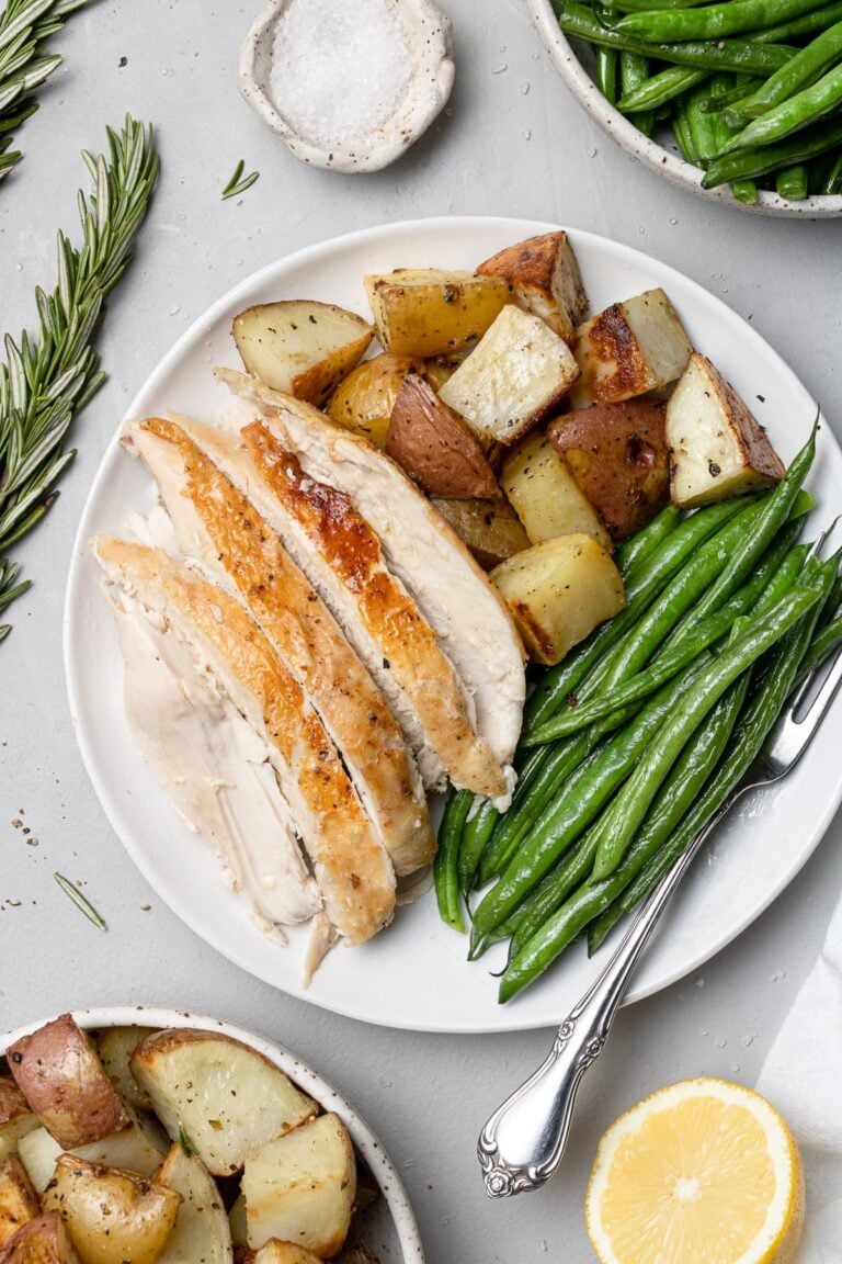 an overhead shot of Crockpot Whole Chicken sliced on a white plate with veggies and potatoes