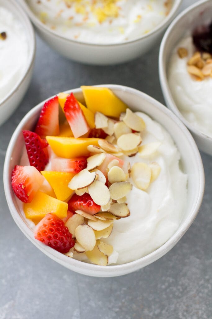 A close up of a strawberry yogurt bowl with 3 other yogurt bowls surrounding it.