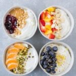 An overhead shot of 4 healthy yogurt bowls on a grey background