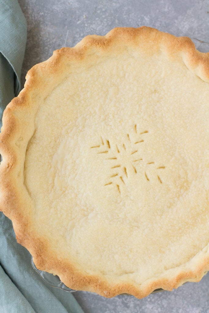 An overhead shot of an Italian Cream Pie on a grey background with a blue linen off to the side
