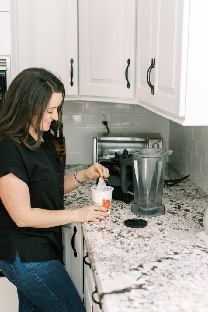 A girl peeling the lid off a daily harvest smoothie