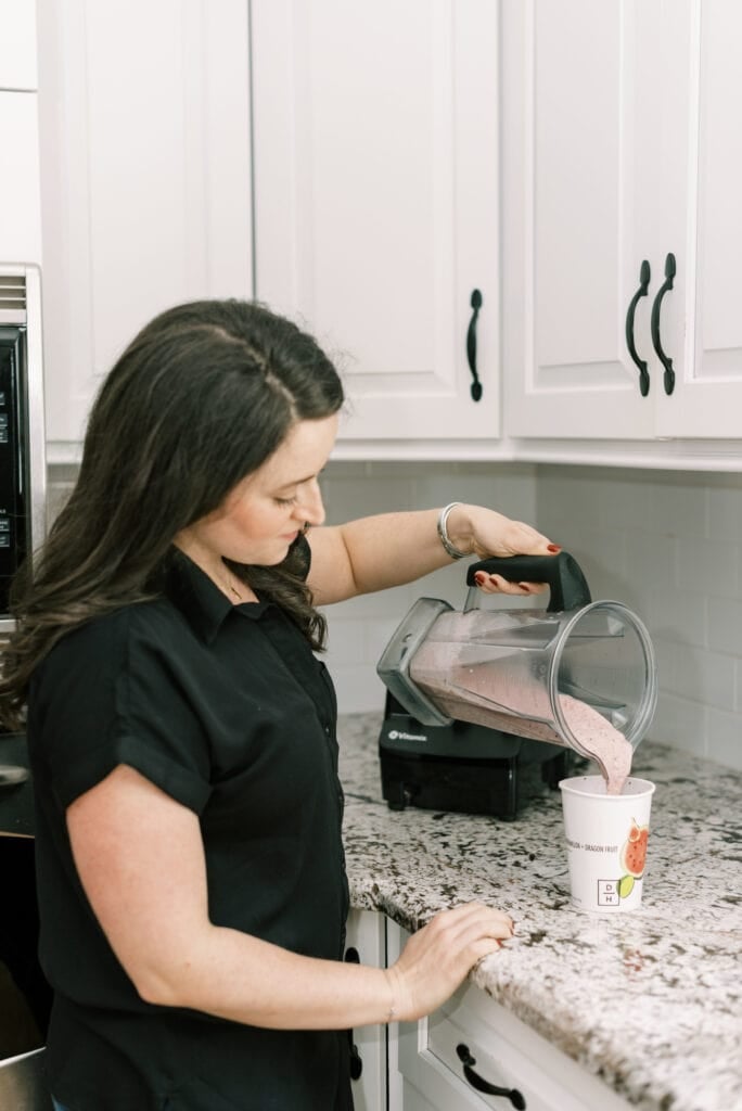 A girl pouring a blender full of daily harvest smoothie into a cup
