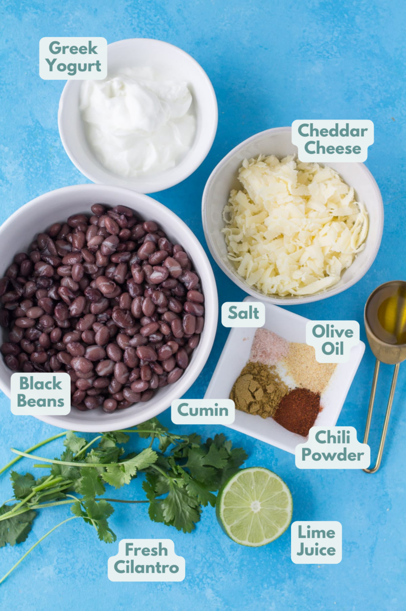 Ingredients for healthy bean dip in small white bowls on a bright blue background