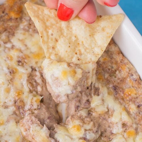 A chip scooping up a bite of healthy bean dip from a dish