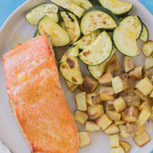 Honey Sriracha Salmon on a white plate with zucchini and potatoes