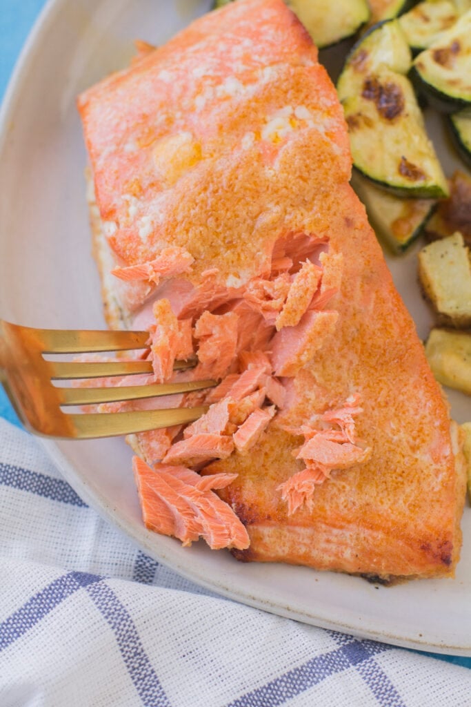 Using a fork to flake pieces of pink fish.