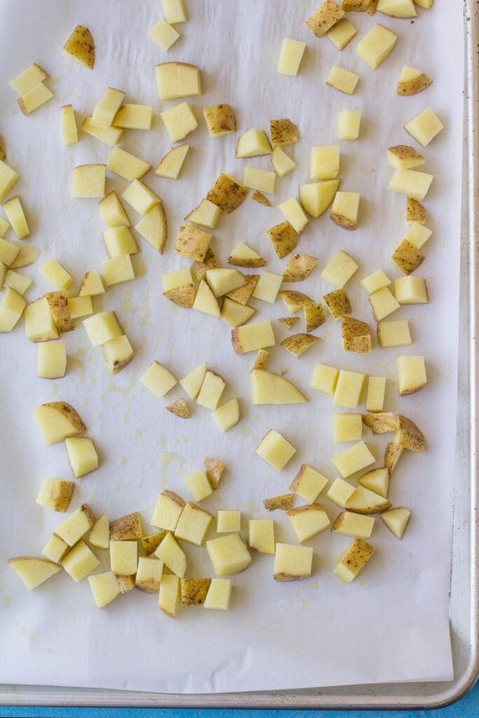Potatoes on a sheet pan baking for honey sriracha salmon