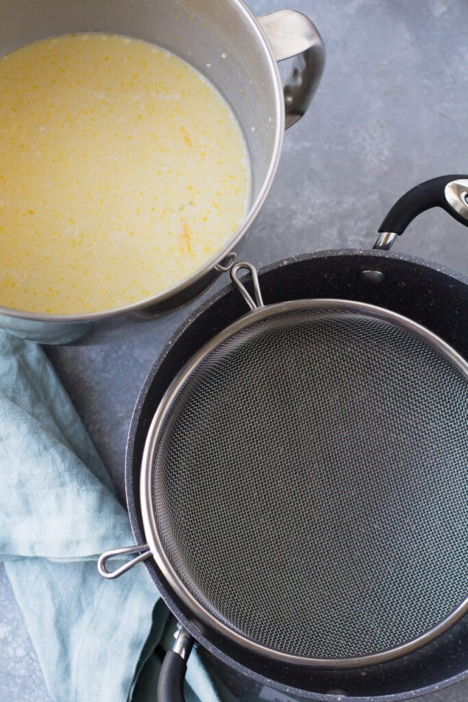 Italian cream pie mixture in a stainless steel bowl and a pot with a strainer
