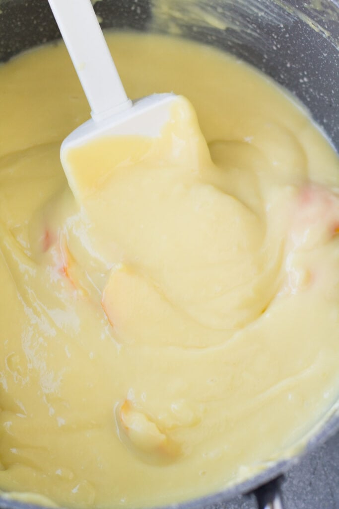 a spatula stirring together italian creamin a pot