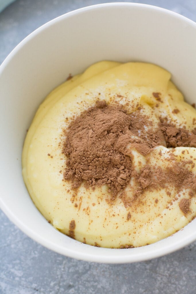 a close up of vanilla italian cream with cocoa powder being stirred in