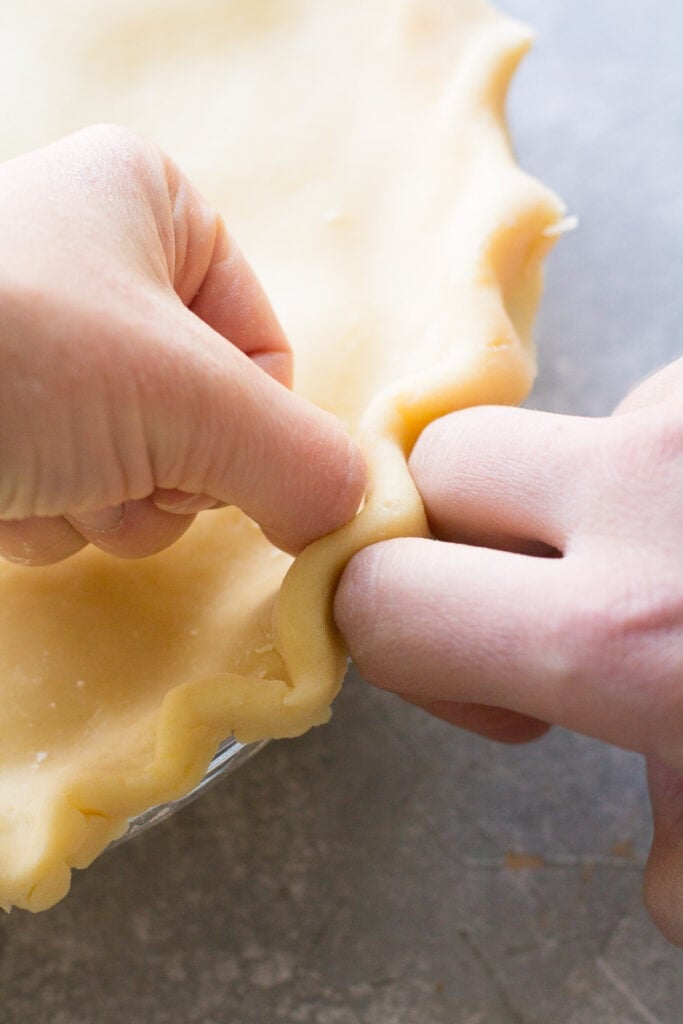 hands forming the top crust on italian cream pie