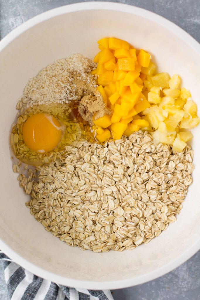 A white bowl of mango baked oatmeal before being mixed together