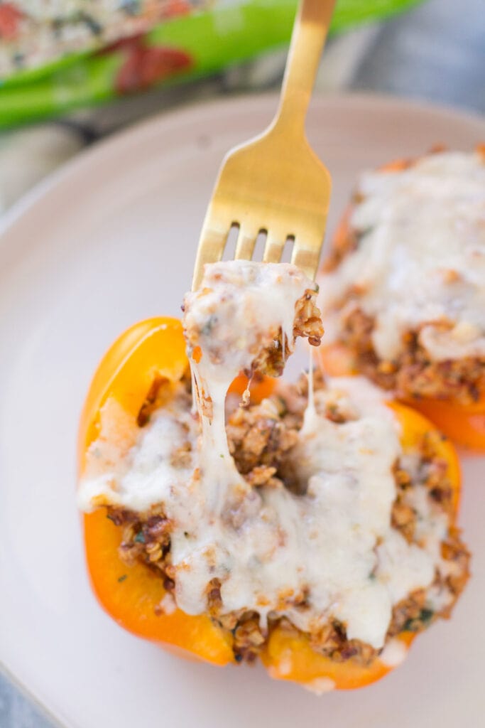 A close up of a fork taking a bite out fof healthy quinoa stuffed peppers