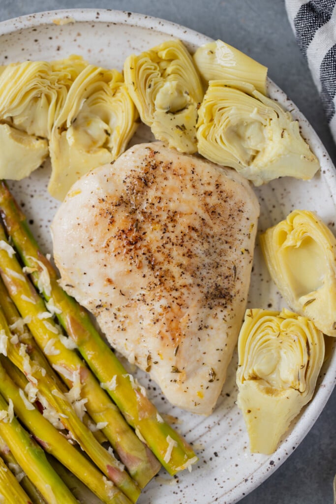 Lemon Artichoke Chicken with artichokes on a plate with asparagus