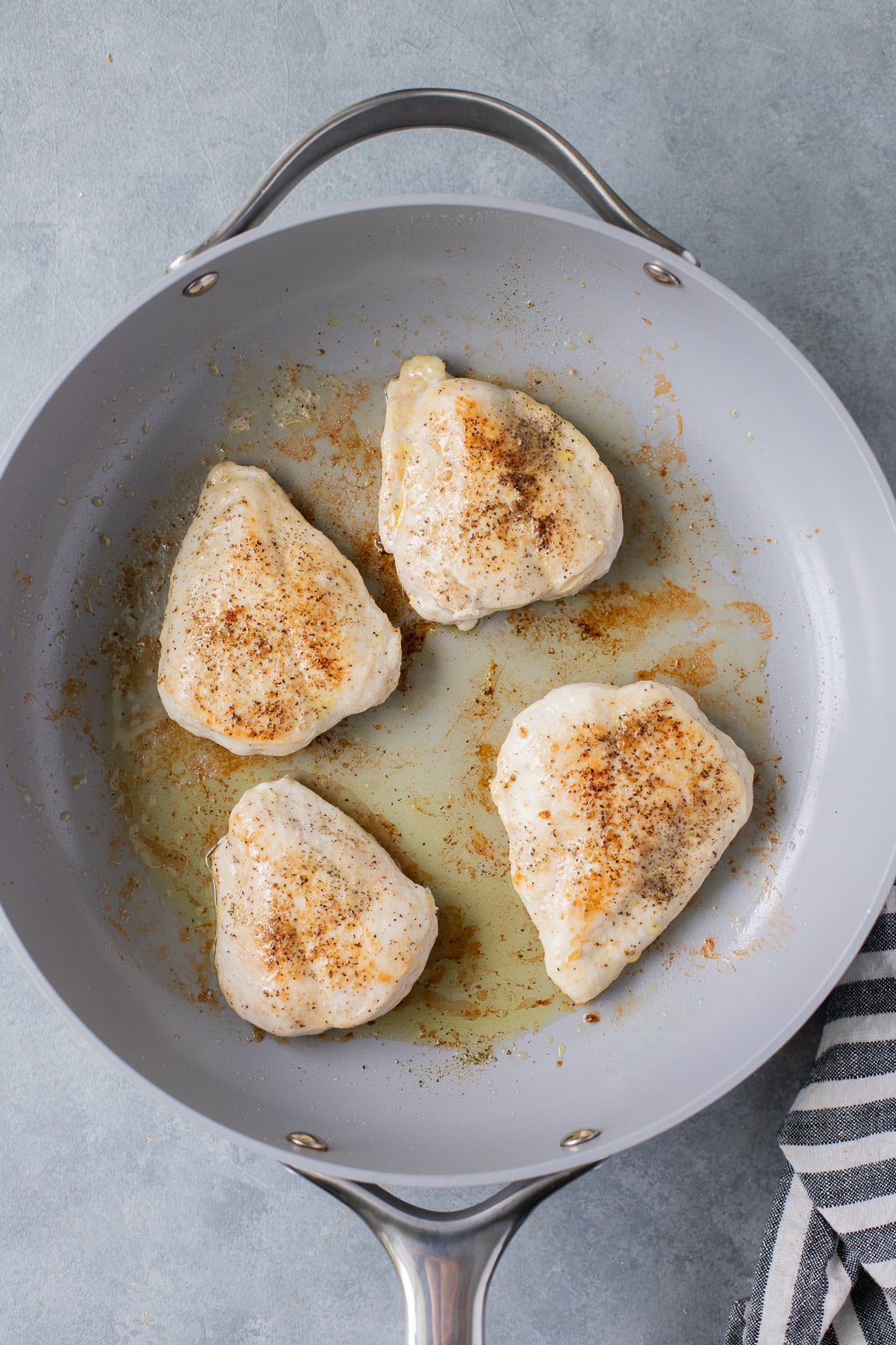 An overhead shot of 4 Chicken Breasts in a pan being cooked for lemon artichoke chicken