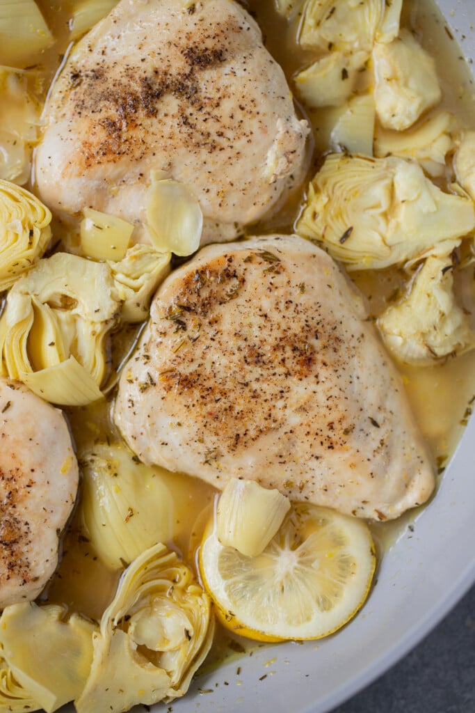 A close up shot of a pan of lemon artichoke chicken in a pan