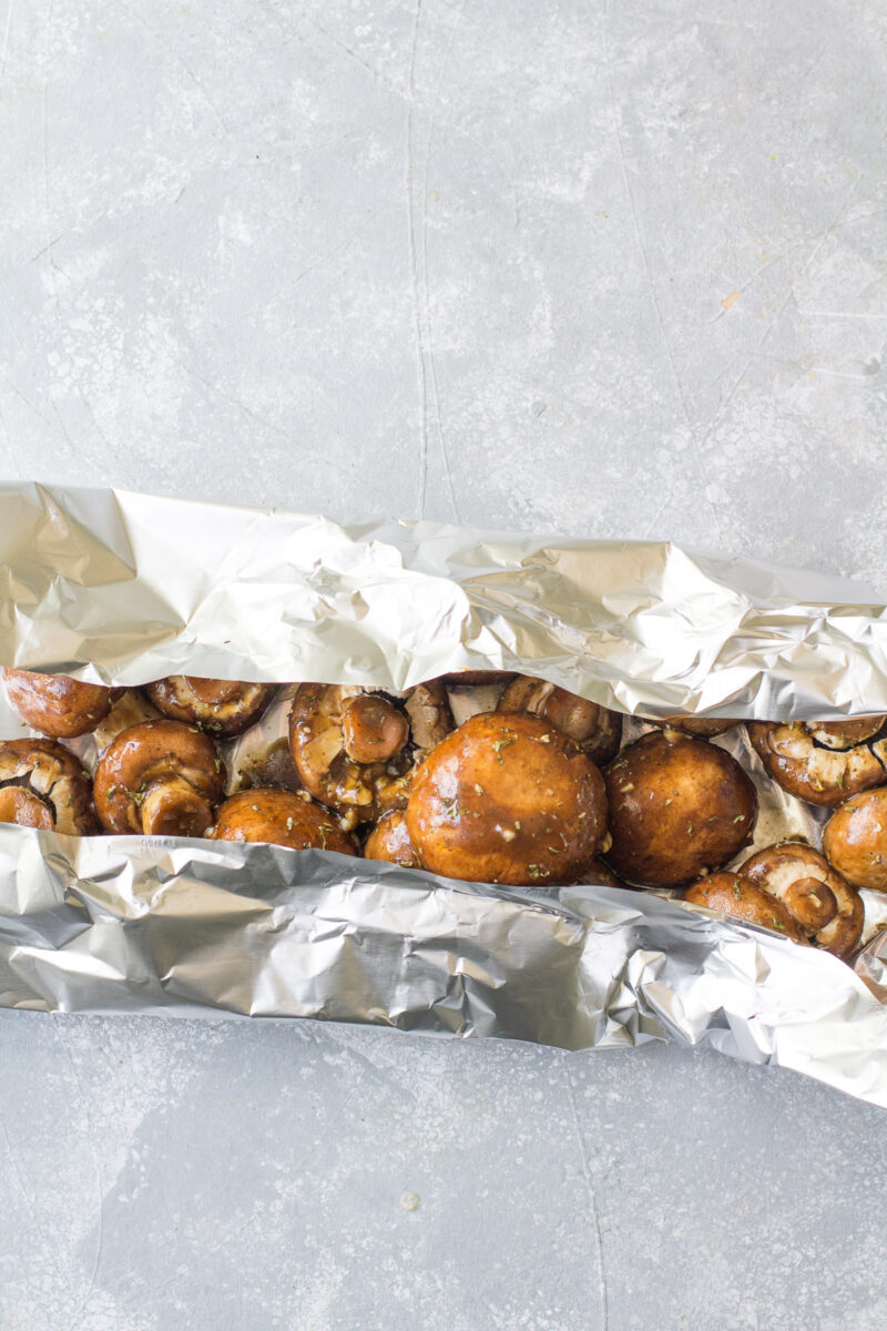 Mushrooms in foil before being grilled with two sides of the foil folded in.