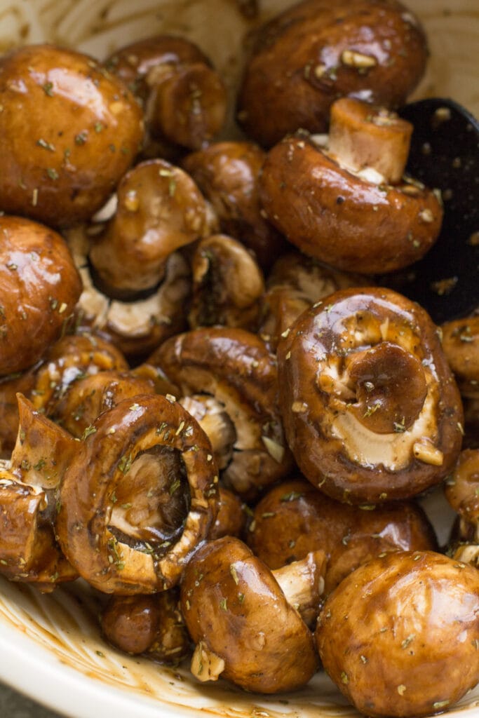 marinated balsamic mushrooms in a white bowl before being grilled