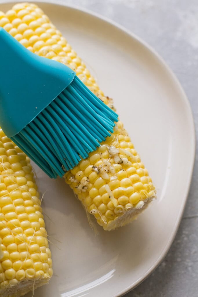 corn being brushed with garlic olive oil