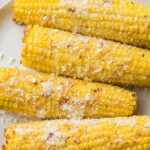 Garlic Parmesan Grilled Corn on a white plate on a grey background